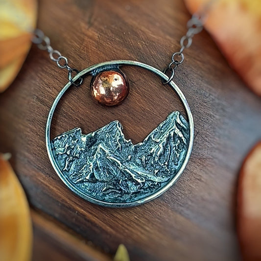 Necklace with moon and mountain design on a wooden surface
